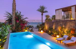 a swimming pool with two chairs and a house at Galei Kinneret Hotel in Tiberias