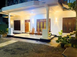 a small white house with two chairs and a porch at Delight Villa - Ahangama in Ahangama