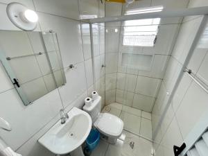 a bathroom with a toilet and a sink and a mirror at Pousada Hebrom in Bertioga +68 photos