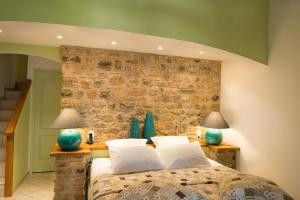 a bedroom with a bed with two lamps and a stone wall at Les Hauteurs du Luberon in Caseneuve