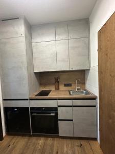 a small kitchen with white cabinets and a sink at Steinbock Apartement in Bad Goisern
