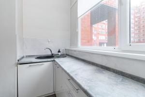 eine weiße Küche mit Spüle und Fenster in der Unterkunft Трех комнатные апартаменты в новом доме рядом с Батырмол in Pawlodar + 17 Fotos