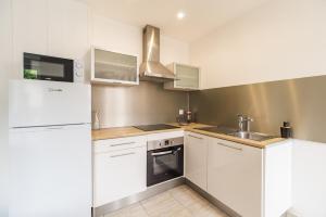 a white kitchen with a sink and a refrigerator at Maison Confortable au coeur de Guingamp in Guingamp