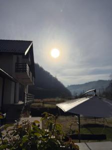 een uitzicht op de zonsondergang vanuit een huis met een parasol bij Casa din lunca 2 in Poiana Mărului