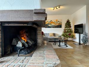 a living room with a fireplace with a christmas tree at Apartment with Balcony & Mountain View in Küblis