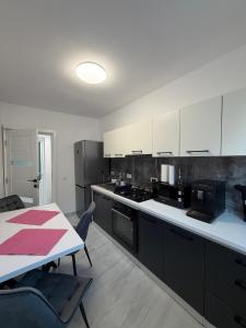 een keuken met witte kasten en een tafel en een tafel en een tafel bij Casa din lunca 2 in Poiana Mărului