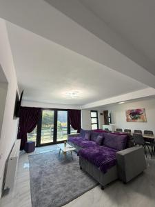 een woonkamer met een paarse bank en een tafel bij Casa din lunca 2 in Poiana Mărului