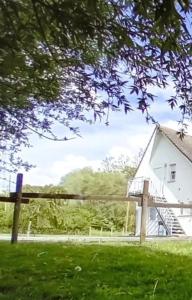 a white house with a wooden fence in a yard at Eeckhoutveld Hébergement 3 chambres in Merckeghem
