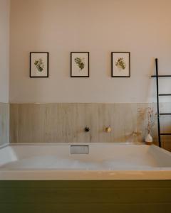 un bagno con vasca e 3 immagini appese alla parete di Landal Whitekirk Hill a North Berwick Altre 19 foto