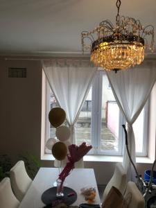 ein Kronleuchter und ein Tisch mit einer Vase mit Blumen darauf in der Unterkunft Danojlic 2 in Višegrad