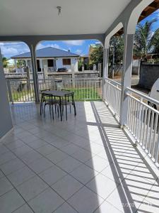 eine Veranda mit einem Tisch und Stühlen darauf in der Unterkunft Villa Le Bananier in Sainte-Rose
