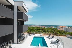 een uitzicht op een gebouw met een zwembad en stoelen bij Mila Deluxe in Novalja