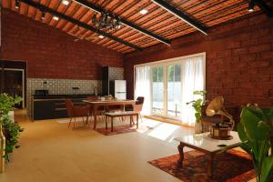 a living room with a table and a brick wall at NOSSA GOA VILLA in MUMBAI GORAI in Mumbai