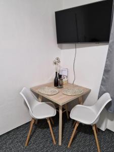 uma mesa com duas cadeiras e uma televisão na parede em Apartmán Rejštejn em RejÅ¡tejn