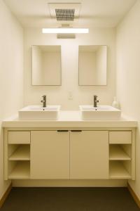 a bathroom with two sinks and two mirrors at Yellow House Niseko in Kutchan +21 photos