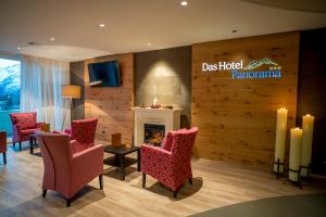 a lobby with red chairs and a fireplace at Hotel Panorama in Hasliberg