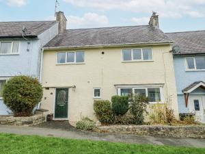 a white house with a green door and bushes at Hafan Hapus in Beaumaris