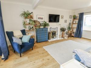 a living room with a blue chair and a tv at Hafan Hapus in Beaumaris