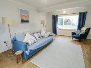 a living room with a blue couch and a chair at Hafan Hapus in Beaumaris