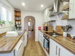 a kitchen with white cabinets and a wooden counter top at Hafan Hapus in Beaumaris