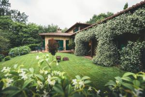 a house covered in ivy with a yard at HolaCamp Camino Apartamentos Turísticos in O Pino 