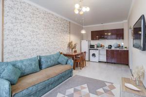 a living room with a couch and a kitchen at Уютная квартира рядом с Батырмол и Баянтау in Pavlodar