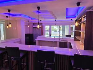 Una cocina con iluminación violeta y una barra con sillas. en THE SEA BREEZE GUEST HOUSE & VENUE HIRE, 11 on SHELBOURNE, en Durban