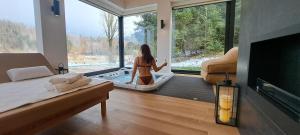 eine Frau in einer Badewanne in einem Zimmer mit Fenster in der Unterkunft Valdora - Forest Oasis 
