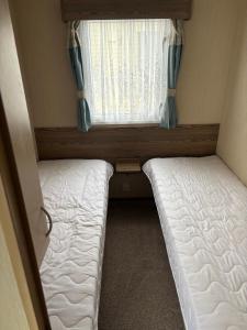 梅布尔索普TLJ Caravan Hires的一间带窗户的小房间里有两张床
