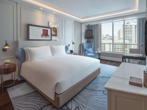 a bedroom with a large white bed and a desk at Sofitel Bangkok Sukhumvit in Bangkok