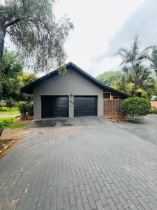 een huis met een garage met een oprit bij Chic 3-bed home with comfort in Pretoria
