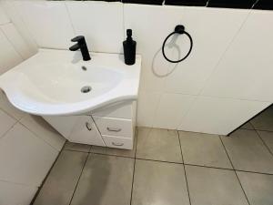 een witte badkamer met een wastafel en een spiegel bij Chic 3-bed home with comfort in Pretoria