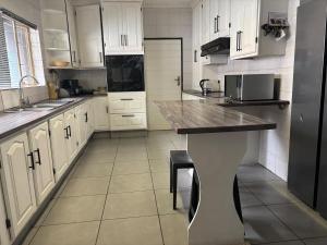 een keuken met witte kasten en een zwarte koelkast bij Chic 3-bed home with comfort in Pretoria +3 foto's