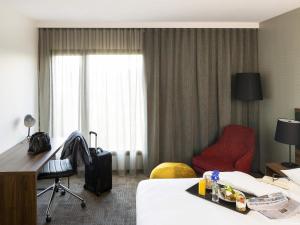 a hotel room with a bed and a red chair at Novotel Sydney International Airport in Sydney