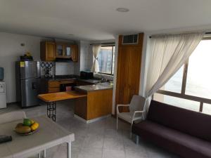 El Peñon Rodadero building - incredible view في Puerto de Gaira: مطبخ وغرفة معيشة مع أريكة وطاولة