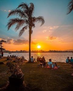a group of people sitting under a palm tree near the water at Bem vindo ao APTO 403 in Florianópolis