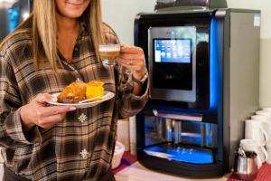 een vrouw die een bord met eten en een glas wijn vasthoudt bij Hotel Bella Italia Piancavallo in Piancavallo