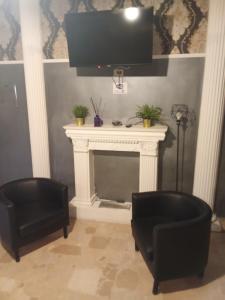 sala de estar con 2 sillas negras y chimenea en Ulisse 1, en Nápoles