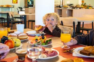 een klein kind zit aan tafel te eten bij Hotel Bella Italia Piancavallo in Piancavallo +19 foto's
