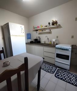 a kitchen with a table and a white refrigerator at Cobertura com 4 quartos e ar condicionado in Cabo Frio