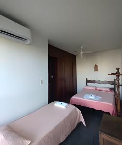 a bedroom with two beds and a tv in it at Cobertura com 4 quartos e ar condicionado in Cabo Frio +8 photos