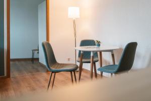 a table with four chairs and a table with a lamp at Anger17-1, Zentrales 2-Zimmer-Apartment in Dessau in Dessau