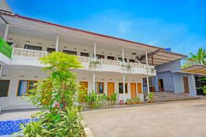 ein großes weißes Gebäude mit einem Balkon und einem Innenhof in der Unterkunft Collection O Subang near Ciater Subang formerly Orchid Villa Ciater in Ciater + 19 Fotos