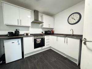 a kitchen with white cabinets and a clock on the wall at Cosy Studio Escape in Ilkeston with Netflix in Ilkeston