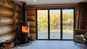 ein Kamin in einer Blockhütte mit einer Glasschiebetür in der Unterkunft Kingfisher Cabin in Broughton in Furness