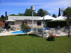 Ein Garten mit Stühlen und Sonnenschirmen neben einem Pool in der Unterkunft Cabañas Midelem in Chascomús