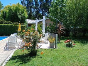 ein Garten mit zwei Stühlen, einem Sonnenschirm und Blumen in der Unterkunft Cabañas Midelem in Chascomús