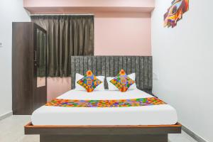 a bedroom with a white bed with colorful pillows at Hotel Brook View in Surat