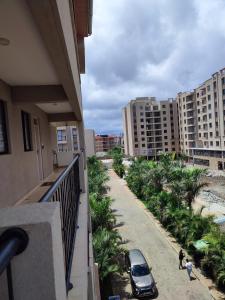 内罗毕Amalia Apartment syokimau的阳台上停着一辆车，街道两旁是棕榈树。