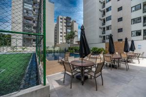 un patio con mesas y sillas con sombrillas y una piscina en Vista Baía do Pontal • Piscina • Ao Lado Gbarbosa, en Pontal de São João da Barra